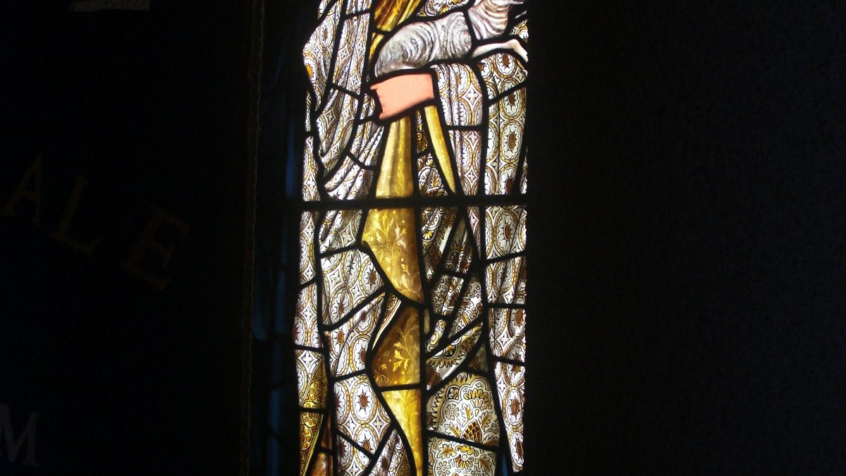 An image of a stained glass window showing a woman posing with the word humility above her